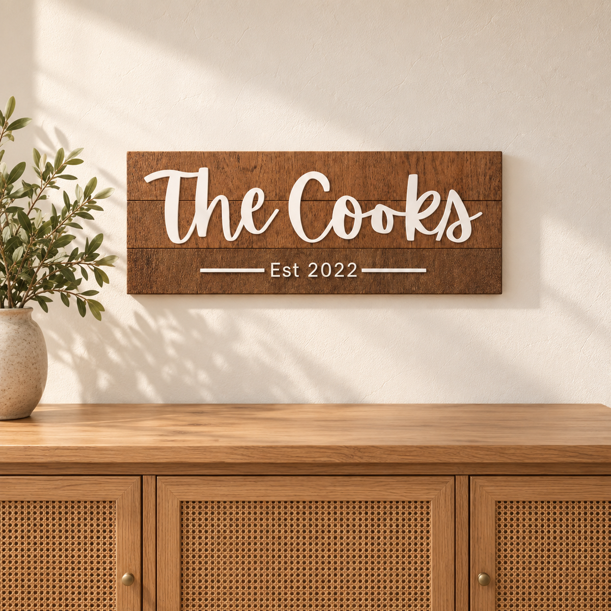 23 by 9 inch personalized walnut family name sign with white The Cooks lettering, wall mounted above a wood console