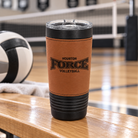 Houston Force Volleyball 20oz cognac leather-wrapped black coffee tumbler, official logo engraved in the leather, photographed on a volleyball gym bench