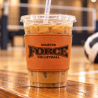Houston Force Volleyball engraved leather cup sleeve fitted around a clear iced coffee cup at a volleyball gym