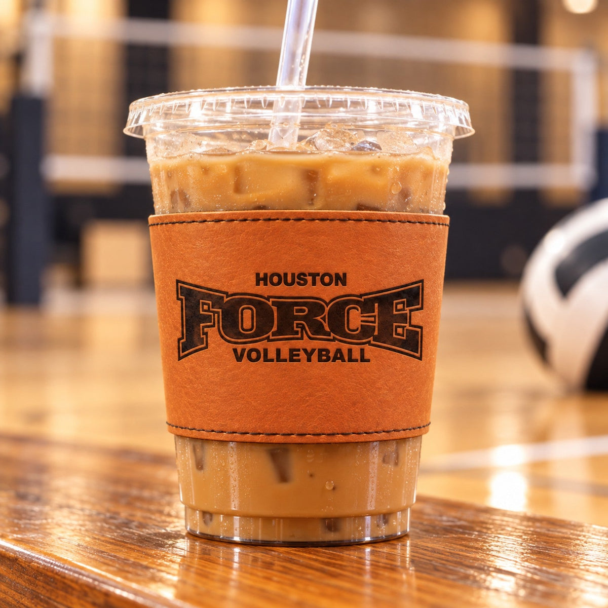 Houston Force Volleyball engraved leather cup sleeve fitted around a clear iced coffee cup at a volleyball gym