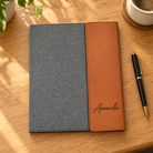 Gray canvas and cognac vegan leather portfolio personalized with Amanda, lying flat on an oak desk
