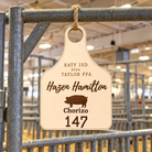 Personalized birch livestock ear tag pen sign hanging by rope from a livestock pen rail